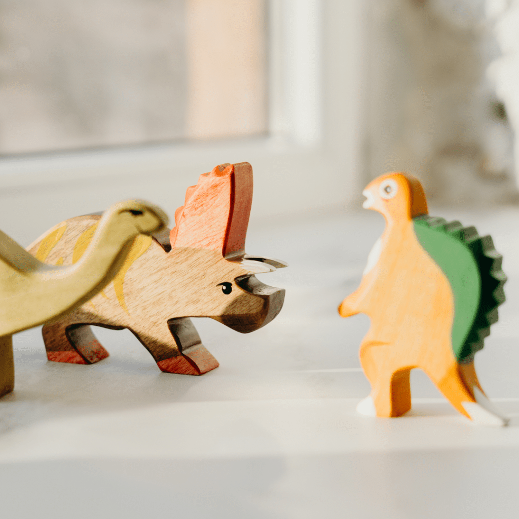 Three wooden dinosaur figures on a windowledge.