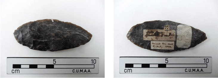 Two photographs of a flint knife, approx 10 centimetres long. On one side there are several label stickers with blurred writing.