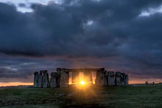 Photograph of Stonehenge at winter solstice with the setting sun shining through the stones