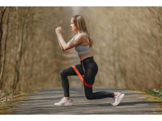 A strong athletic woman using resistance bands whilst exercising in a park