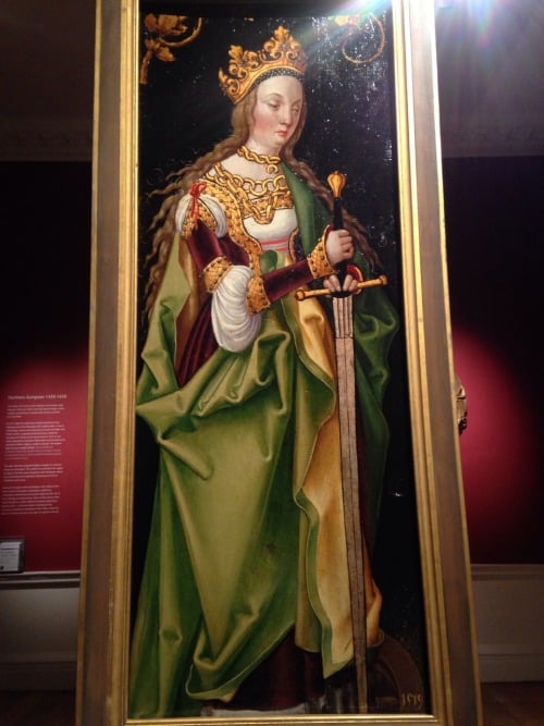 Image of a painting of a grumpy looking queen holding a sword.